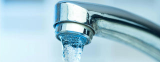Close-up of cold water flowing from a chrome faucet, household water usage concept