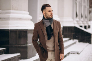 Stylish man in brown winter coat and scarf outdoors in snowy urban setting
