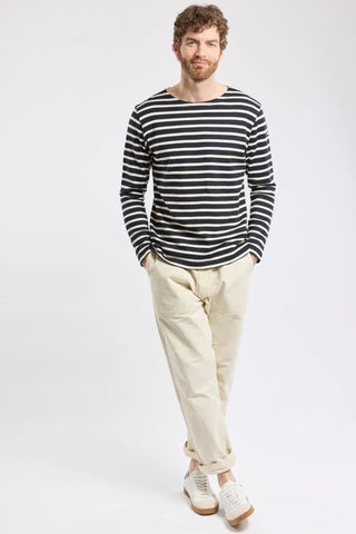 Man wearing navy and white striped long sleeve shirt, beige pants, and white sneakers
