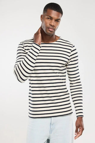 Man wearing a navy and white striped long-sleeve shirt and light jeans against a white background.