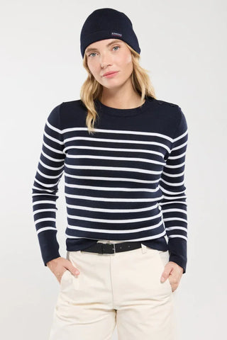 Woman wearing navy and white striped sweater, navy beanie, and light pants.