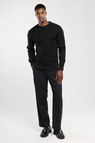 Man wearing black button-shoulder sweater and black trousers, stylish menswear fashion