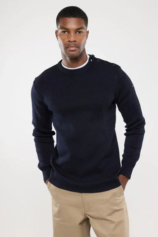 Man wearing a navy blue knit sweater with shoulder buttons and beige pants