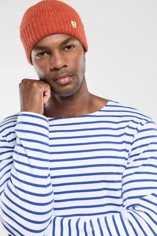 Man in blue and white striped shirt and orange knit beanie with anchor patch