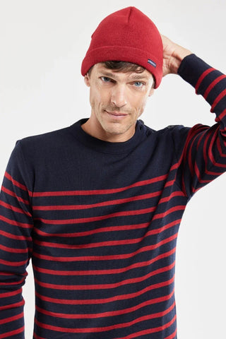 Man wearing a red beanie and navy sweater with red stripes, casual winter fashion.