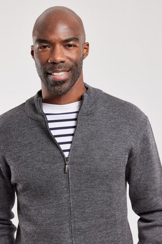 Man wearing a gray wool zip-up cardigan over a striped shirt, studio background
