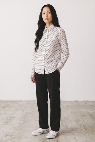 Modèle portant une blouse Le Capitaine D'a Bord en coton blanc à carreaux noirs, manches longues et broderies délicates.