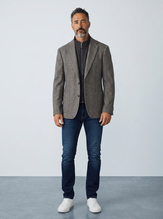 Homme portant un veston en laine gris Le Capitaine D'a Bord avec col zippé détachable, jean bleu et baskets blanches