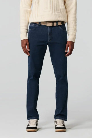 Man wearing dark blue straight-leg jeans with beige belt and sneakers