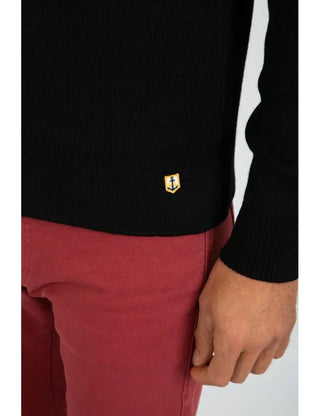 Close-up of black knit cardigan with anchor patch, worn with red pants