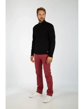 Man wearing a black zip-up wool cardigan, red pants, and white sneakers, standing in studio