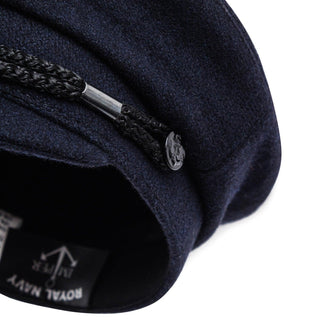 Close-up of navy wool captain's cap with braided trim and anchor button detail