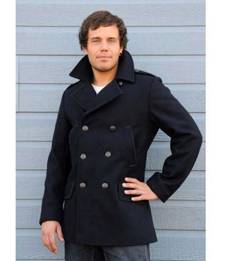 Man wearing a navy wool peacoat with double-breasted buttons, standing against a blue wall