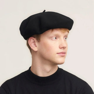 Man wearing classic black Basque beret, side view, simple beige background