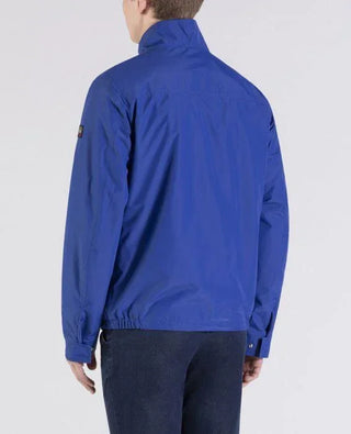 Man wearing blue nylon blouson jacket with stand collar and jeans, back view