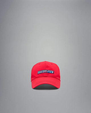 Red nylon yachting cap with embroidered logo patch on front, displayed on gray background