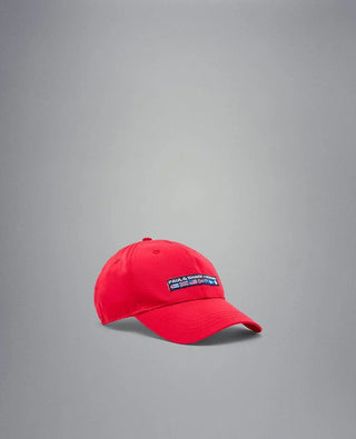 Red nylon yachting cap with embroidered patch and nautical flags on a gray background