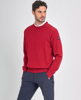 Man wearing a red crew neck sweater with shoulder patches and left arm logo patch